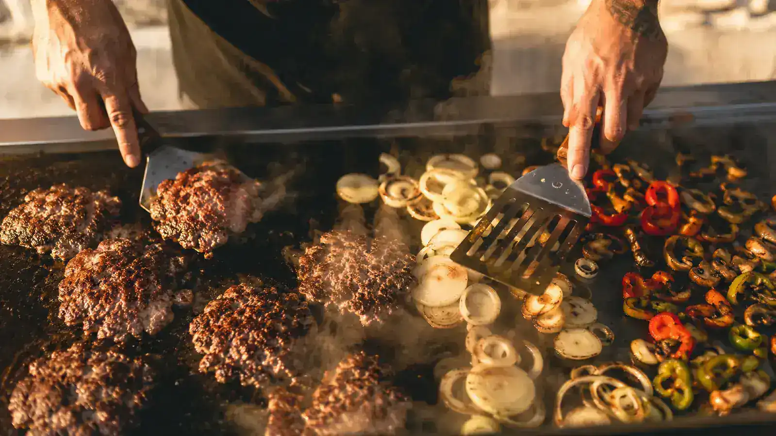 Backyard pitmaster organizing flat top griddle tools on a Blackstone griddle station at golden hour
