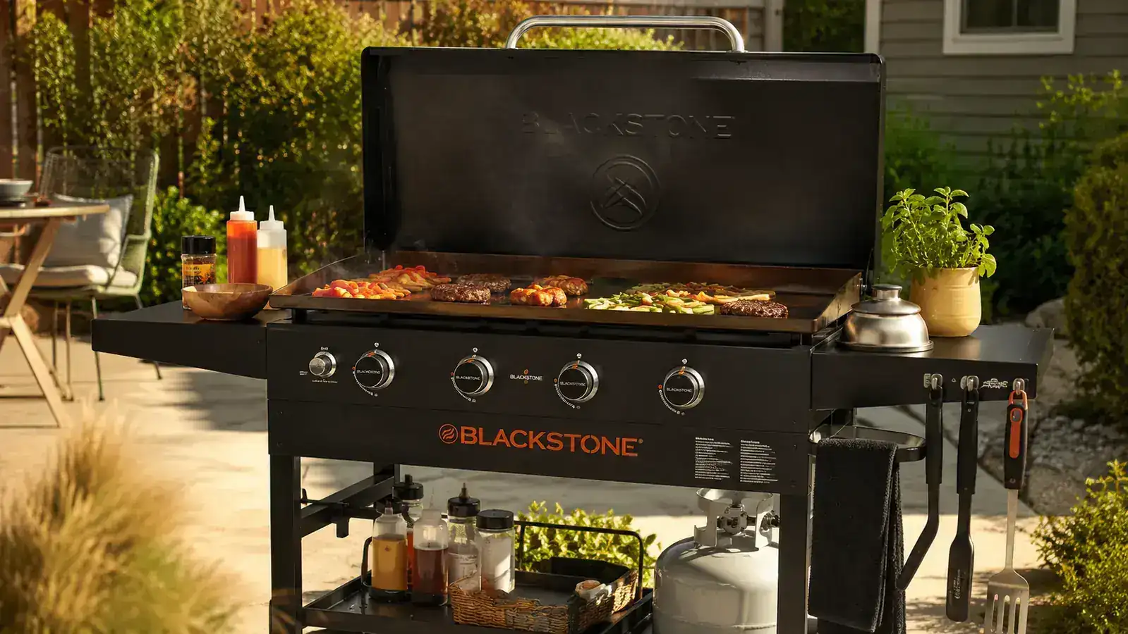 Backyard Blackstone flat top griddle set up outdoors on a sunny Memphis afternoon with a full set of griddle tools laid out on the side shelf